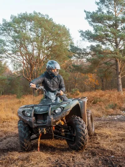 Quad bike rider navigating a muddy track through the trees